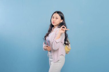 Bir kadın elinde bir tablet tutuyor ve onu işaret ediyor. Gülümsüyor ve mutlu.