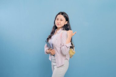 Bir kadın elinde bir tablet tutuyor ve onu işaret ediyor. Gülümsüyor ve mutlu.