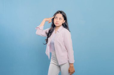 Pembe gömlekli ve beyaz pantolonlu bir kadın kameraya bakıyor. Bir şey düşünüyor ya da düşünüyor.