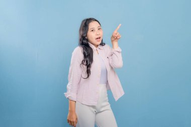 Bir kadın pembe gömlek ve beyaz pantolon giyerken bir şeyi işaret ediyor. Hedef gösterilen konu hakkındaki merak ve ilgi kavramı