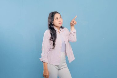 Bir kadın pembe gömlek ve beyaz pantolon giyerken bir şeyi işaret ediyor. Hedef gösterilen konu hakkındaki merak ve ilgi kavramı