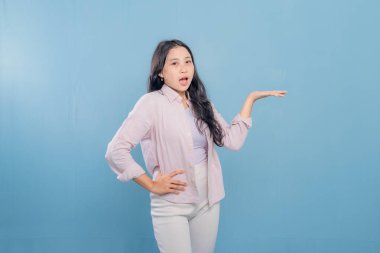 Bir kadın pembe gömlek ve beyaz pantolon giyerken bir şeyi işaret ediyor. Hedef gösterilen konu hakkındaki merak ve ilgi kavramı