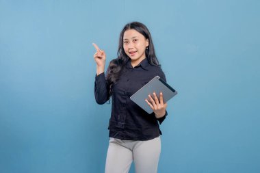 Bir kadın elinde bir tablet tutuyor ve onu işaret ediyor. Gülümsüyor ve mutlu.