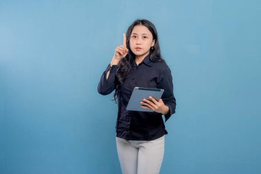 Bir kadın elinde bir tablet tutuyor ve onu işaret ediyor. Gülümsüyor ve mutlu.