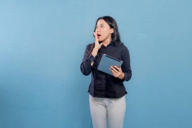 Bir kadın elinde bir tablet tutuyor ve ağzı açık. Şok ya da şaşkınlık içinde.