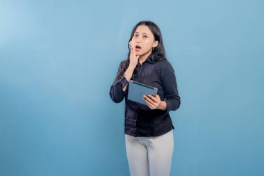 Bir kadın elinde bir tablet tutuyor ve ağzı açık. Şok ya da şaşkınlık içinde.