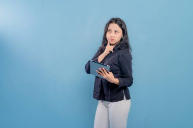 Bir kadın elinde bir tablet tutuyor ve ona şaşkın bir ifadeyle bakıyor. Bir şey bulmaya ya da karar vermeye çalışıyor gibi görünüyor. Tablet onun önüne konur.