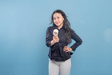 Bir kadın elinde küçük bir vantilatör tutuyor. Gülümsüyor ve mutlu.