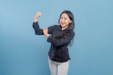 Bir kadın kolları havada poz veriyor, kaslarını gösteriyor. Güven ve güç kavramı