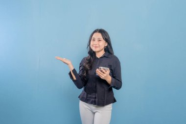 Bir kadın cep telefonunu tutar ve önemli bir şeye işaret eder. Gülümsüyor ve mutlu. Modern teknoloji ve iletişim kavramı