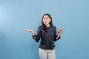 Bir kadın cep telefonunu tutar ve önemli bir şeye işaret eder. Gülümsüyor ve mutlu. Modern teknoloji ve iletişim kavramı