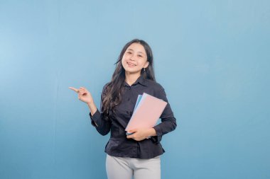 Bir kadın elinde bir yığın kitap ya da kağıt tutarken bir şeyi işaret ediyor. O, siyah bir gömlek ve beyaz pantolon giyiyor. Önem kavramı ve odak