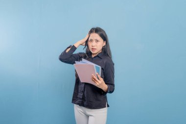 Bir kadın kameraya bakarken bir kitap okuyor. Okuduğu bir şeye şaşırmış ya da şok olmuş.