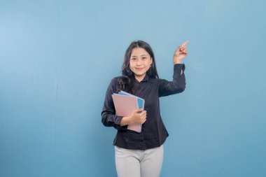 Bir kadın elinde bir yığın kitap ya da kağıt tutarken bir şeyi işaret ediyor. O, siyah bir gömlek ve beyaz pantolon giyiyor. Önem kavramı ve odak