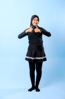 Siyah etek ve siyah pantolon giyen bir kadın. Parmağıyla işaret ediyor.