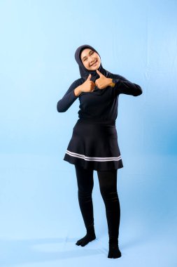 Siyah etek ve siyah pantolon giyen bir kadın. Parmağıyla işaret ediyor.