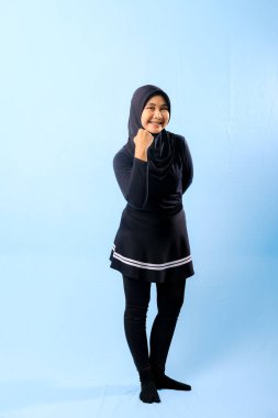 Siyah elbiseli, siyah eşarplı ve siyah pantolonlu bir kadın.