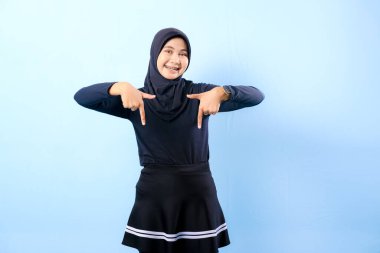 Siyah etek giyen ve sağı gösteren siyah bir başörtüsü olan bir kız. Gülümsüyor.