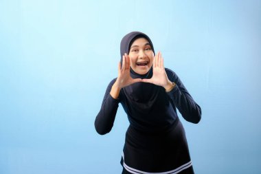 Siyah tesettürlü bir kadın elleriyle jest yapıyor. Bağırarak ya da bir şeyler söyleyerek bir jest yapıyor.