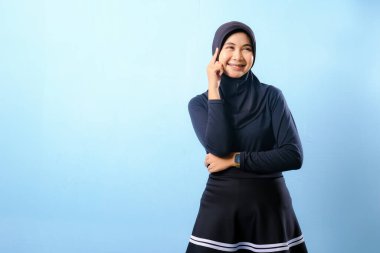 Siyah etek ve siyah başörtüsü takan bir kadın. Gülümsüyor ve sağa bakıyor.