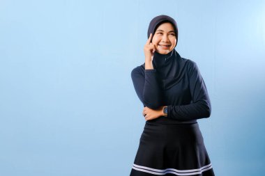 Siyah etek ve siyah başörtüsü takan bir kadın. Gülümsüyor ve sağa bakıyor.