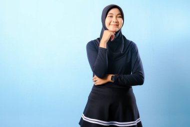 Siyah etek ve siyah başörtüsü takan bir kadın. Gülümsüyor ve sağa bakıyor.