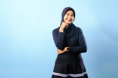 Siyah etek ve siyah başörtüsü takan bir kadın. Gülümsüyor ve sağa bakıyor.