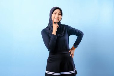 Siyah etek ve siyah başörtüsü takan bir kadın. Gülümsüyor ve sağa bakıyor.