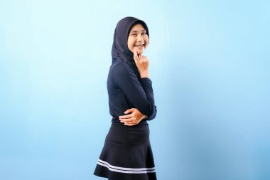 Siyah etek ve siyah başörtüsü takan bir kadın. Gülümsüyor ve sağa bakıyor.