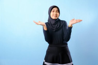 Siyah tesettürlü bir kadın elleri cebinde kameraya bakıyor. Dalgın bir ruh hali içinde.