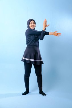 Siyah elbiseli bir kadın kollarını yana doğru açıyor. Siyah çorap ve siyah pantolon giyiyor.