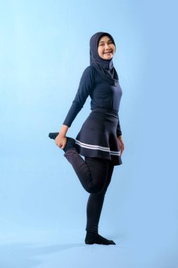 Siyah elbiseli bir kadın kollarını yana doğru açıyor. Siyah çorap ve siyah pantolon giyiyor.