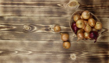 Ahşap bir arka planda sepetteki büyük çiğ organik soğanlar. Üst Manzara. Boşluğu kopyala.