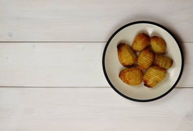 Beyaz tabakta ev yapımı Hasselback Patates. Beyaz tablo, boşluk kopyala, üst görünüm.