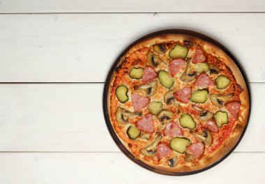 Ahşap bir arka planda, tahta bir tahtada jambonlu ve mantarlı pizza servis ediliyor. Üst manzara, düz uzanma