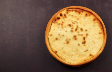 Koyu arkaplanda kuru üzüm ve süzme peynirli yuvarlak turta. Üst manzara, düz uzanma