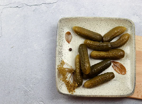 Pickled cucumbers on a light rectangular plate on a wooden cutting board on a light gray background. Top view, flat lay — Stock Image Pickled Cucumbers Light Rectangular Plate Wooden Cutting Board Light Gray Royalty Free Stock Images
