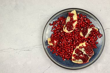 Hafif arkaplandaki bir tabakta nar tohumları. Üst manzara, düz uzanma