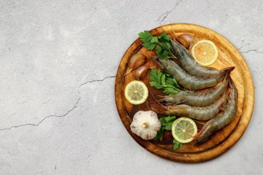 Çiğ karidesler ahşap bir zeminde, tahta bir tahtanın üzerinde servis edilir. Üst manzara, düz uzanma