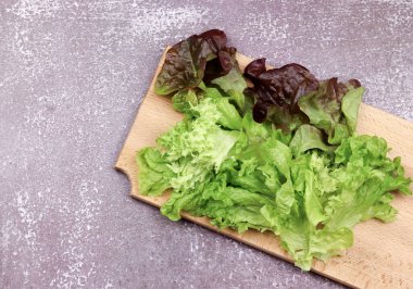 Koyu ahşap bir arka planda, ahşap bir tahtada marul. Üst manzara, düz uzanma