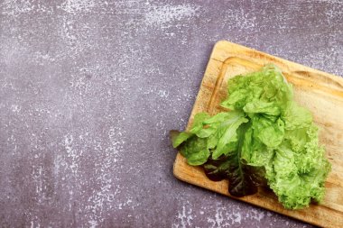 Koyu ahşap bir arka planda, ahşap bir tahtada marul. Üst manzara, düz uzanma