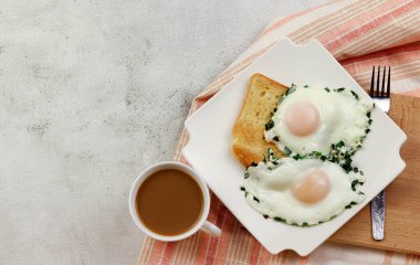 Kahvaltı - yeşil soğanlı sahanda yumurta, açık gri arka planda bir fincan kahveyle birlikte bir tabakta tost. Üst manzara, düz uzanma