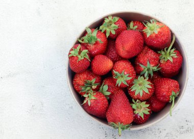Açık gri arka planda bir kasede çilek. Üst manzara, düz uzanma