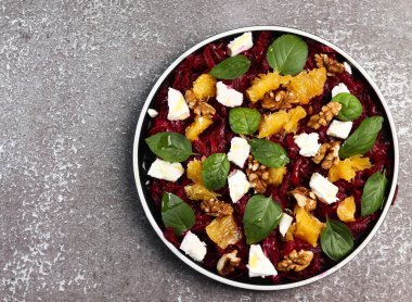 Portakallı pancar salatası, ceviz, fesleğen ve siyah arka planda yuvarlak bir tabakta nane. Üst manzara, düz uzanma