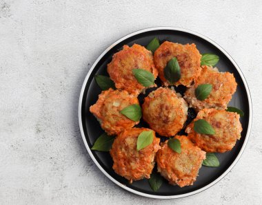 Açık gri arka planda yuvarlak tabakta domates soslu köfteler. Üst manzara, düz uzanma