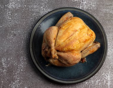 Koyu bir arka planda, yuvarlak bir tabakta tüm tavuğu pişirdim. Üst manzara, düz uzanma