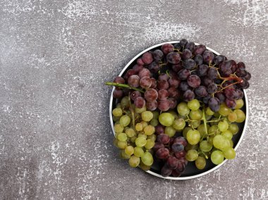 Koyu bir arka planda yuvarlak bir tabakta çeşitli olgun üzümler. Üst manzara, düz uzanma