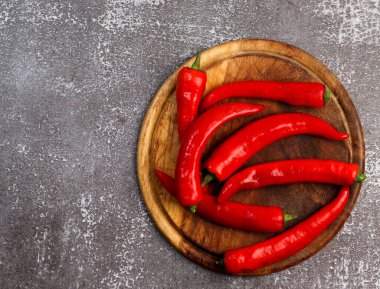 Yuvarlak ahşap kesme tahtasında koyu kırmızı kırmızı biber. Üst manzara, düz uzanma