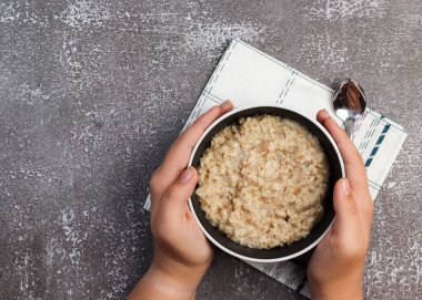 Kasede yulaf ezmesi, ellerinde koyu bir arka planda. Üst manzara, düz uzanma
