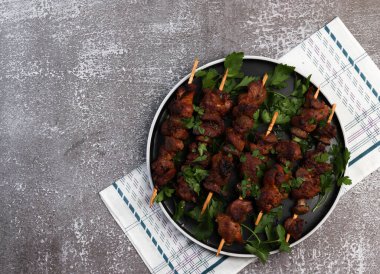 Izgara et - şiş kebaplar tahta şiş şişler üzerinde yuvarlak bir tabakta koyu bir arka planda. Üst manzara, düz uzanma